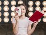 smiling-girl-sitting-front-stage-light-holding-mask-book